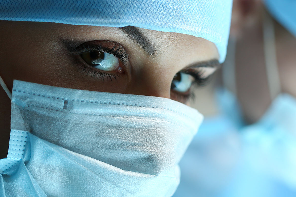 特写的女性医务专业人员戴着外科手术帽和口罩