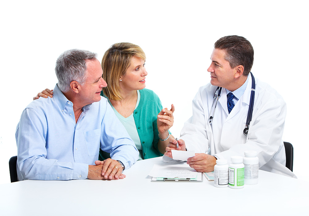 一对中年夫妇微笑着对着医学专家说话，桌上放着医学报告和药瓶
